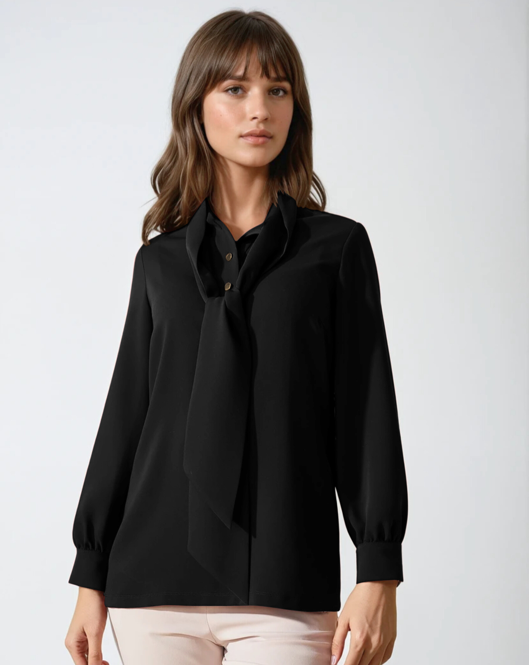 Woman wearing a black blouse with a tie detail on a white background
