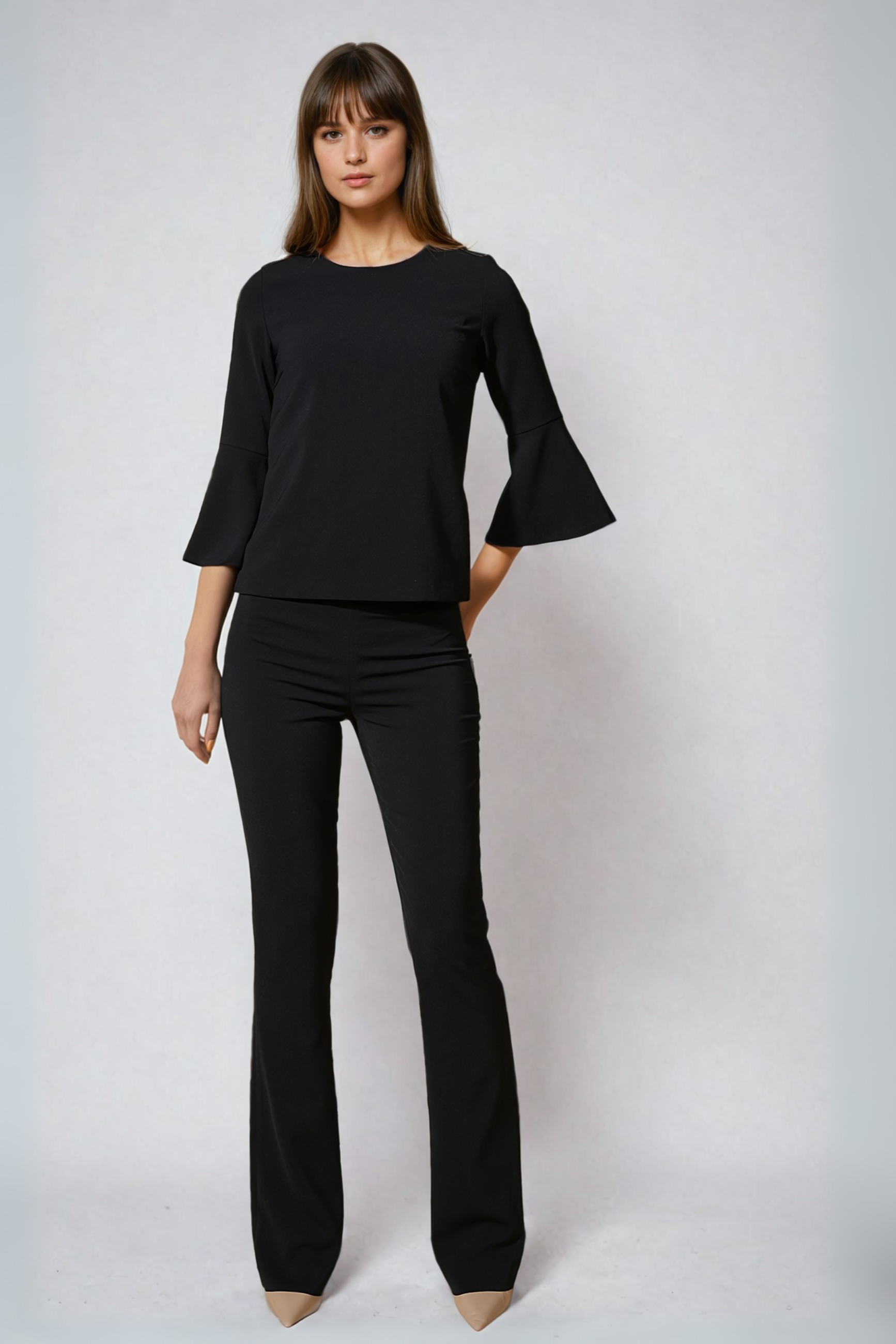 Woman wearing a black outfit with flared sleeves against a white background